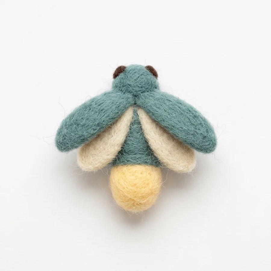 A felt firefly with a teal body and a glowing yellow tail